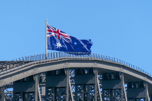 The Australian flag flies on the Sydney Harbour Bridge on a sunny, Spring afternoon.  This image was taken from Milsons Point on the western side of the bridge.