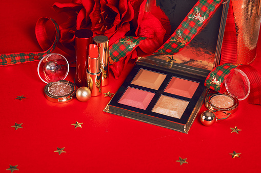 composition with makeup products and Christmas decor on red background. Christmas sale of beauty products concept.