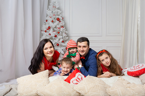 Parents with kids in a Christmas photo session. Studio shooting before the holidays