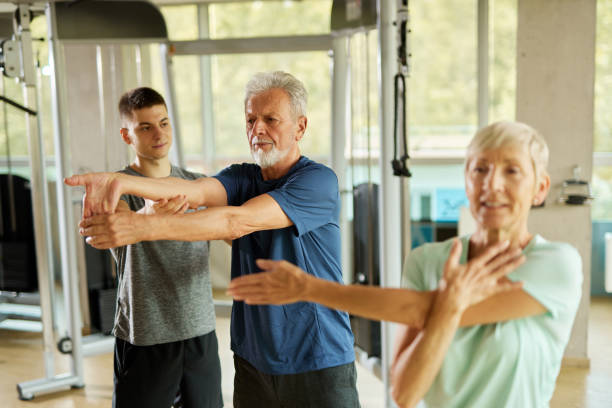 istock Senior couple doing stretching exercises with personal trainer at the gym 1433527852