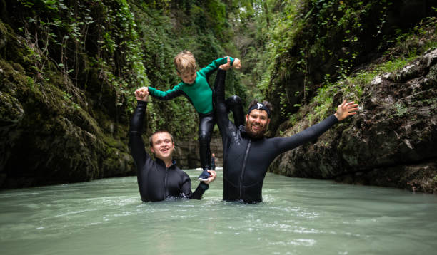 a man with a child in wetsuits in a canyon with a river man with a child in wetsuits in a canyon with a river canyoneering stock pictures, royalty-free photos & images
