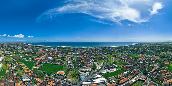 Aerial view from above overlooking the town of Canggu and the pacific ocean on the west coast of Bali, Indonesia. Seen a warm day in the summer.