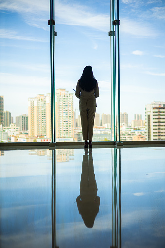 Businesswoman standing near window looking city skyline