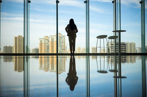 Businesswoman standing at window looking city skyline