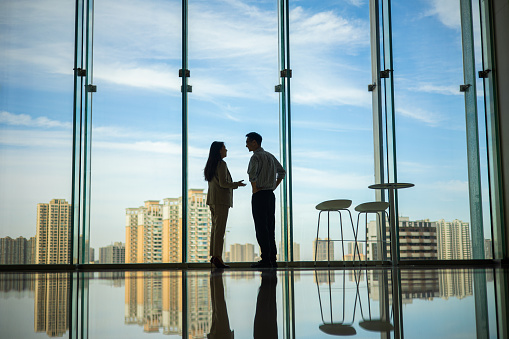 Businesswomen and man discuss in front of window