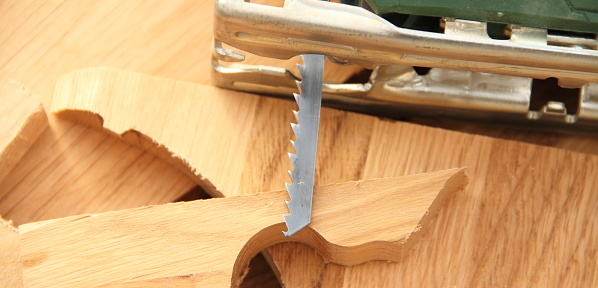 Mature male carpenter using a hand sander to sand down a wooden surface in his workshop.