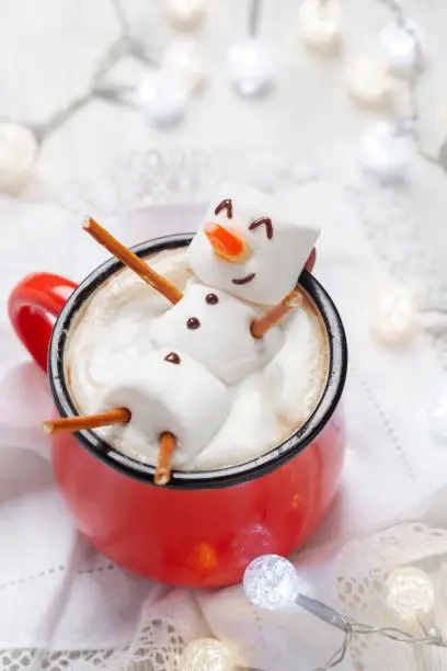 Red mug with hot chocolate with melted marshmallow snowman