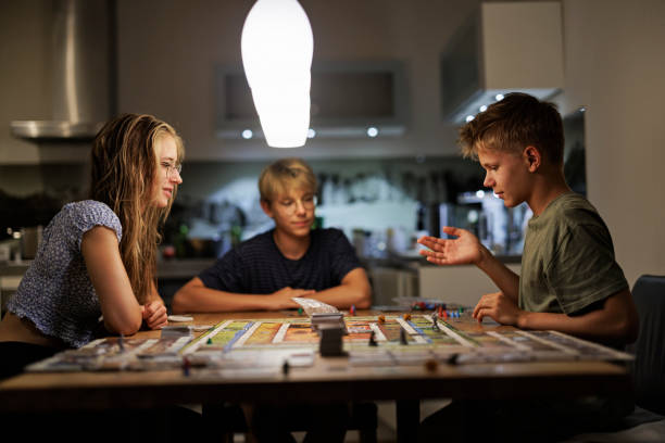 自宅で一緒に大きなボードゲームをしているティーンエイジャー - leisure games dice indoors table ストックフォトと画像