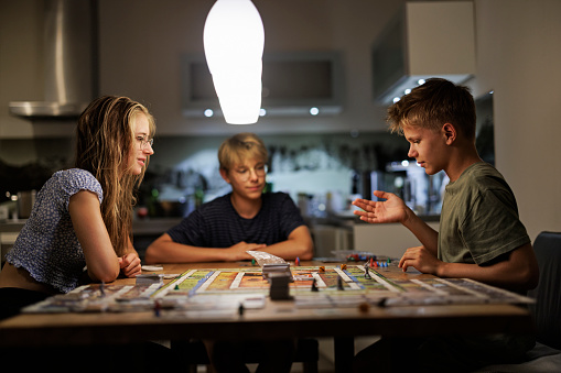 Three teenage kids playing large board game on the table.
Shot with Canon R5