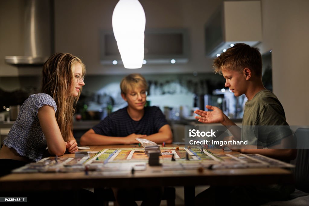 Teenagers playing large board game together at home Three teenage kids playing large board game on the table.
Shot with Canon R5 Board Game Stock Photo