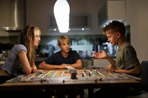 Three teenage kids playing large board game on the table.
Shot with Canon R5