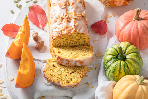 Homemade pumpkin pound cake with almonds and white glaze. Halloween cake made of pumpkin and spices.