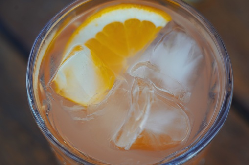 A closeup of an orange fruity cocktail with big ice cubes in a glass