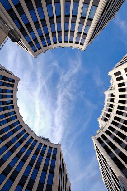 A low angle shot of urban circular round buildings with windows  under blue sky with clouds