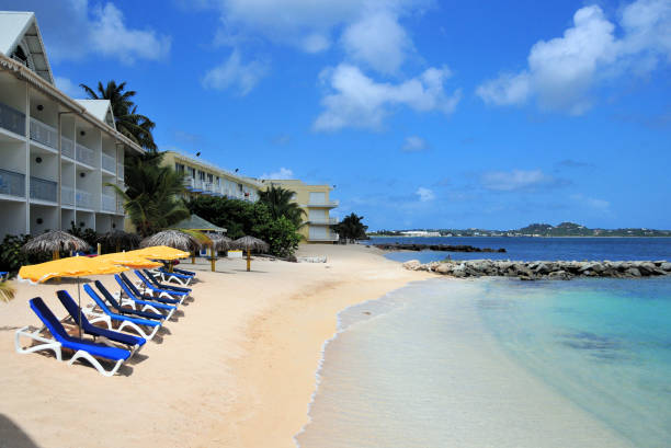 Marigot, Collectivity of Saint Martin / Collectivité de Saint-Martin, French Caribbean: beach on Marigot bay - line of beachfront hotels, golden sand, deckchairs and parasols - tropical vacation.