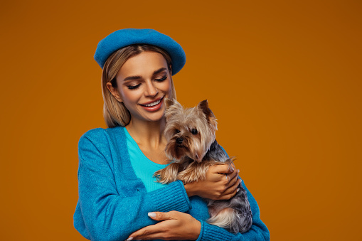 Studio portrait of smiling young woman holding little dog