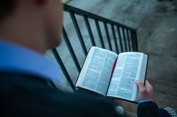 istock Guy reading a Bible sitting on the stairs outdoors on a blurred background 1433555853