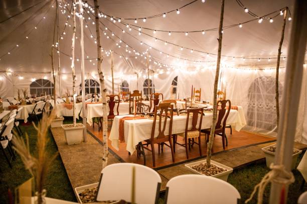 istock Wedding venue tent with dinner equipment on tables and string lights 1433561189