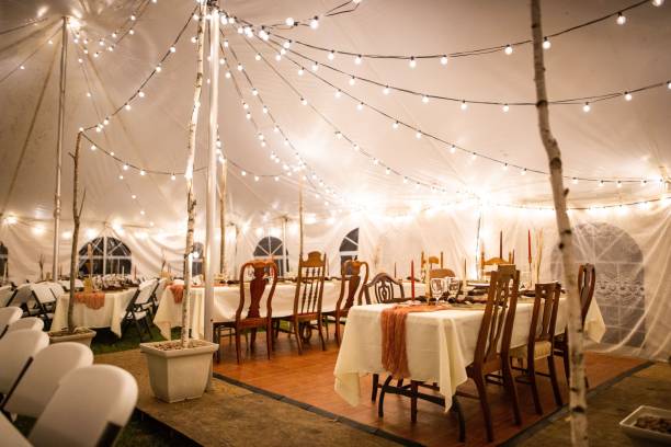 istock Wedding venue tent with dinner equipment on tables and string lights 1433561190