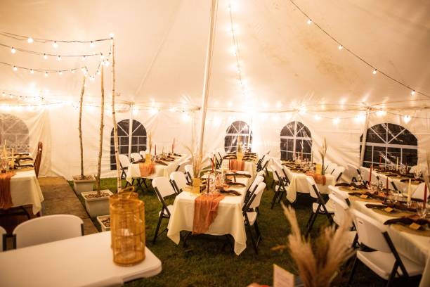 istock Wedding venue tent with dinner equipment on tables and string lights 1433561193