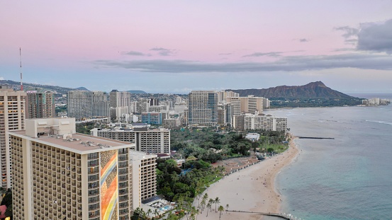 An aerial view of cityscape Honolulu surrounded by buildings and water during sunset