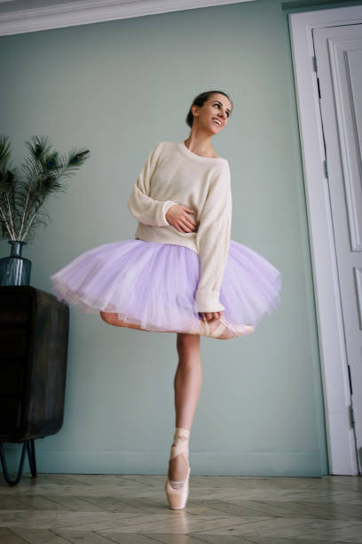 ballerine pose montrant ses jambes dans la pièce devant le miroir en chaussures à pointes et tutu - flying contemporary dancing dancer photos et images de collection