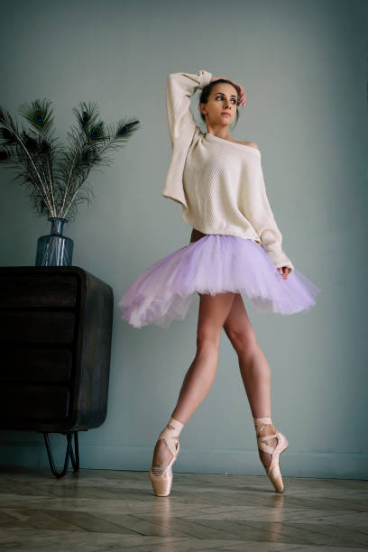 ballerine pose montrant ses jambes dans la pièce devant le miroir en chaussures à pointes et tutu - flying contemporary dancing dancer photos et images de collection