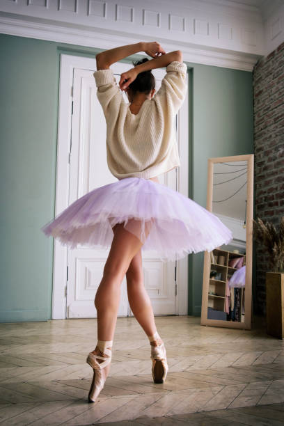 ballerine pose montrant ses jambes dans la pièce devant le miroir en chaussures à pointes et tutu - flying contemporary dancing dancer photos et images de collection