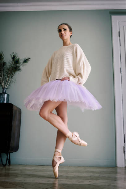 ballerine pose montrant ses jambes dans la pièce devant le miroir en chaussures à pointes et tutu - flying contemporary dancing dancer photos et images de collection