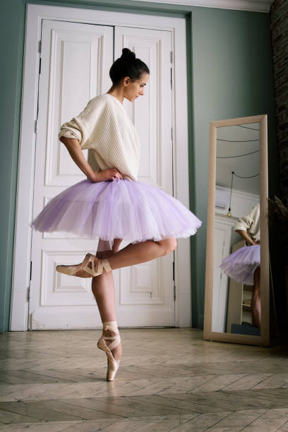 ballerine pose montrant ses jambes dans la pièce devant le miroir en chaussures à pointes et tutu - flying contemporary dancing dancer photos et images de collection