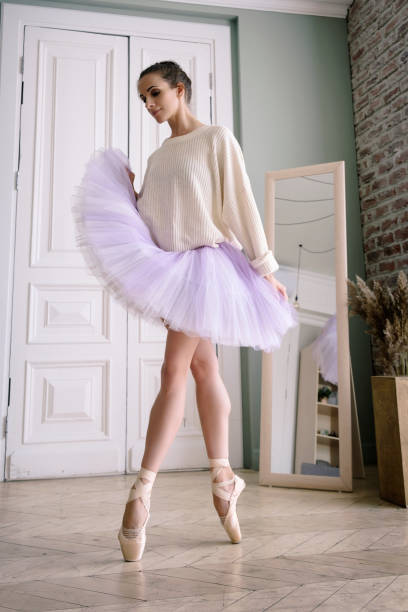 ballerine pose montrant ses jambes dans la pièce devant le miroir en chaussures à pointes et tutu - flying contemporary dancing dancer photos et images de collection