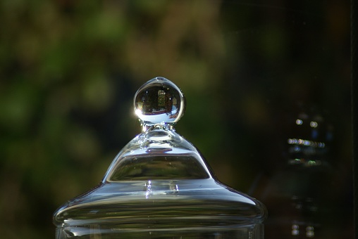 A closeup of a glass jar lid with a blurred background.