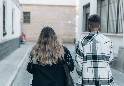 A shallow focus of  the back view of a couple walking away in an alley