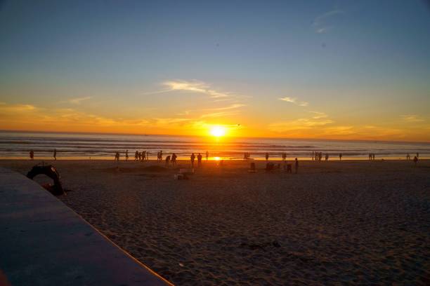 istock Bright golden sunset on a beach with silhouettes of people walking around 1433565708
