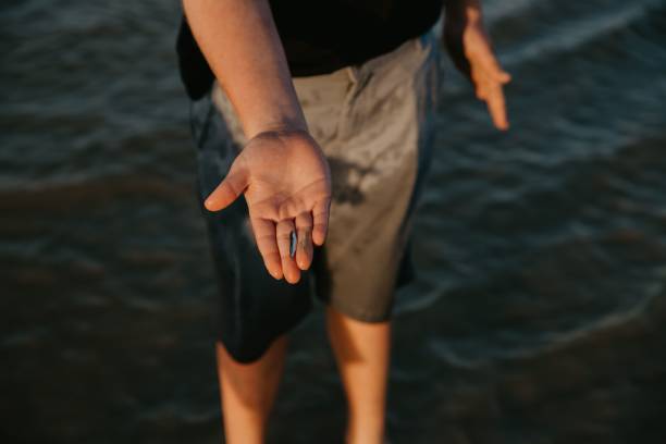 istock Man standing on the seacoast and holding a tiny fish in his hand 1433566660
