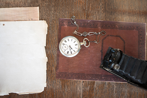 Top view of a old camera and old pocket watch on old book and desk
