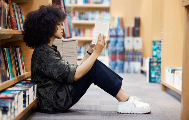 istock University, library book and girl student learning, reading and studying by school bookshelf for knowledge and education. Campus, college and young teenager with novel, information and intelligence 1433572470