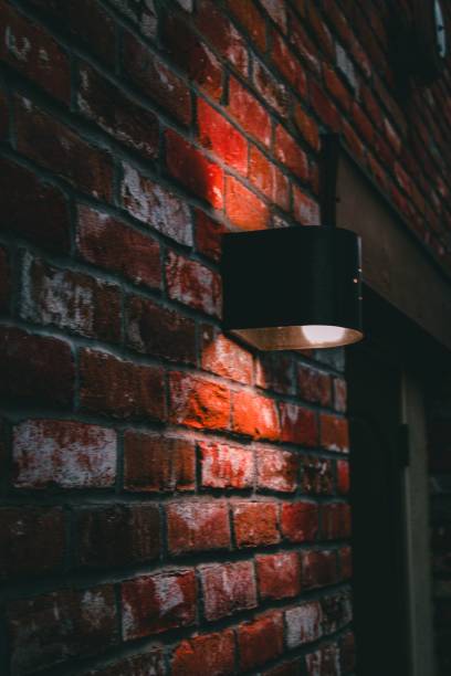 istock Vertical shot of an illuminated lightbulb on a brown brick wall 1433572514
