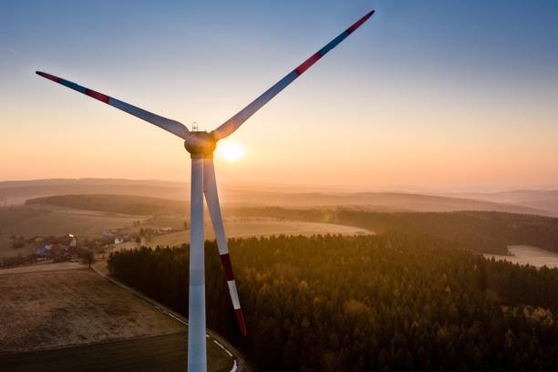 istock White windmill closeup at sunrise, sun rays flooding around and making mist, pink sky background 1433573221