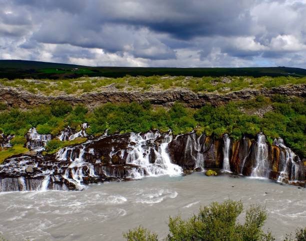 Hraunfossar waterfall with a cloudy sky in the background on a gloomy day, Island The Hraunfossar waterfall with a cloudy sky in the background on a gloomy day, Island hraunfossar stock pictures, royalty-free photos & images
