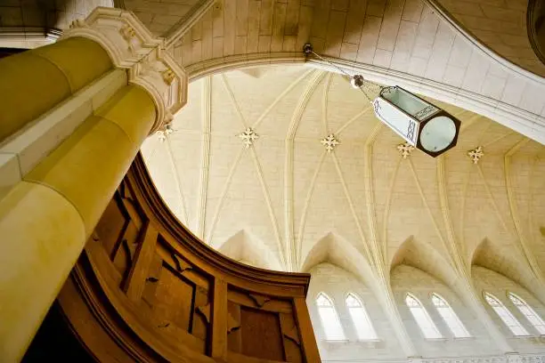 A low angle shot of Victorian-style lantern hanging from spacious ancient library ceiling
