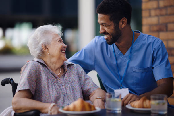Caregiver having breakfast with his client at cafe. stock photo