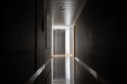 Dark and mysterious corridor in a hospital building.Door room perspective in lonely quiet building with light on black and white style. horror landscape concept.