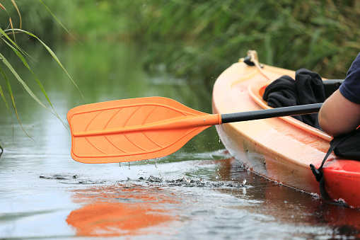 Kayak oar with water drops close-up. River kayaking in summer day concept. Active vacations.