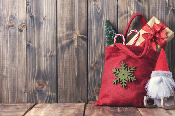 Hanger Christmas bags with christmas decorations on wooden wall.