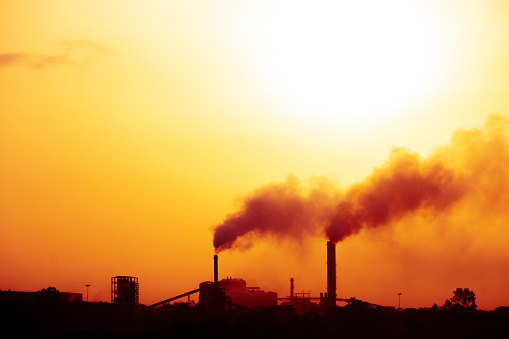Aerial view of high smoke stack with smoke emission. Plant pipes pollute atmosphere. silhouette background.