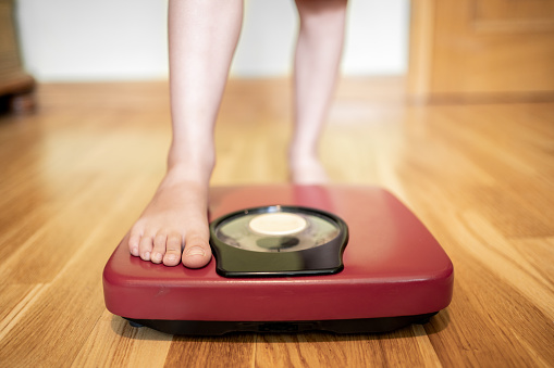 Close up of girl measures weight on a weight scale.