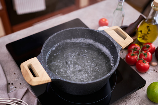 Boiling water in a cooking pot an a pan on a induction stove at domestic kitchen.