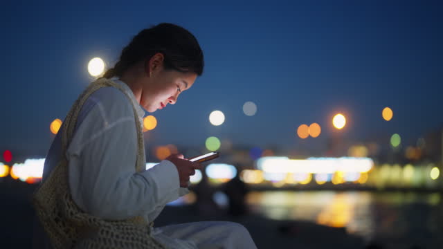 Young woman using smart phone in city at night