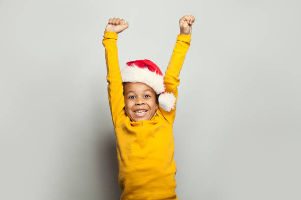 Little black child win-win! Kid boy in Santa hat having fun on white background